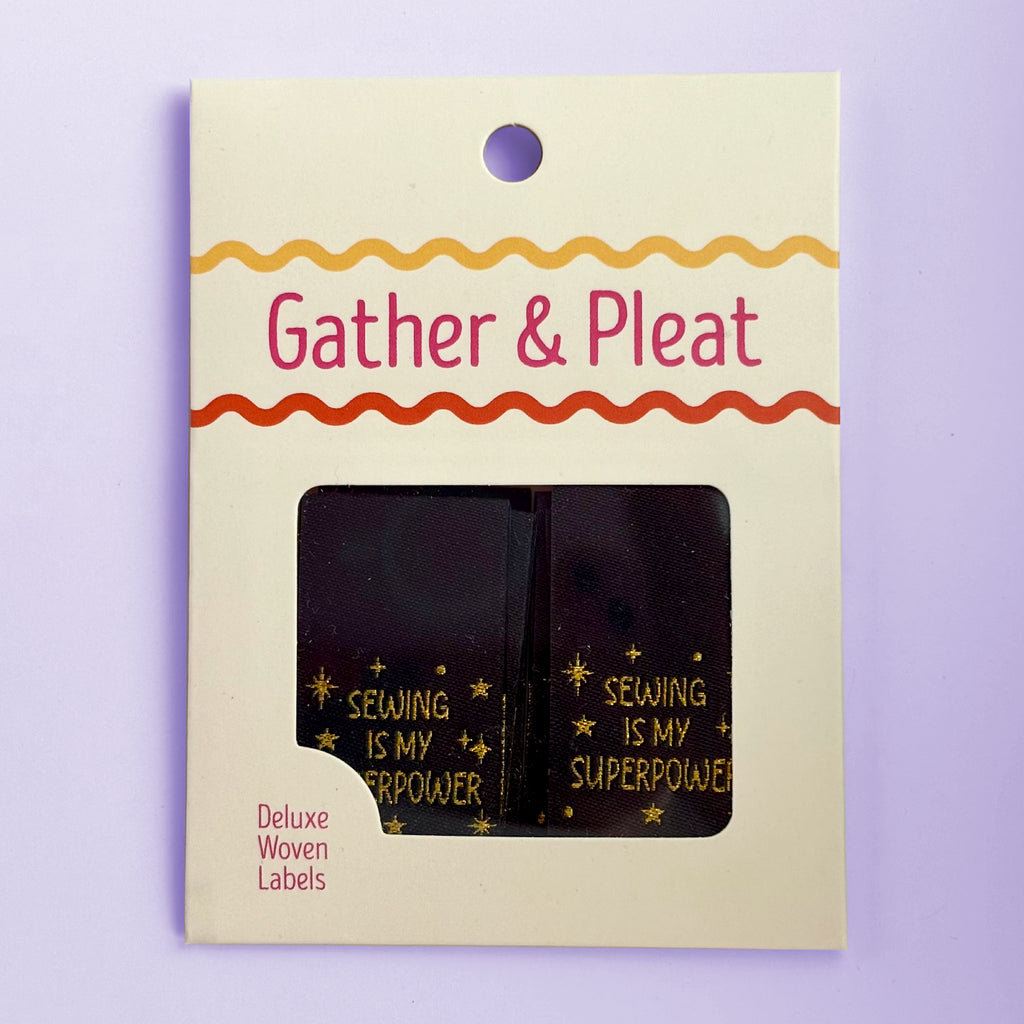 Pack of six 'Sewing Is My Superpower' woven sewing labels in Gather & Pleat retail packaging, on a lilac background.